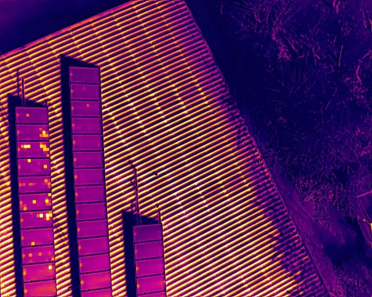 Thermalbild einer PV-Anlage auf einem Hallendach: einzelne Zellen heben sich als warme Punkte ab